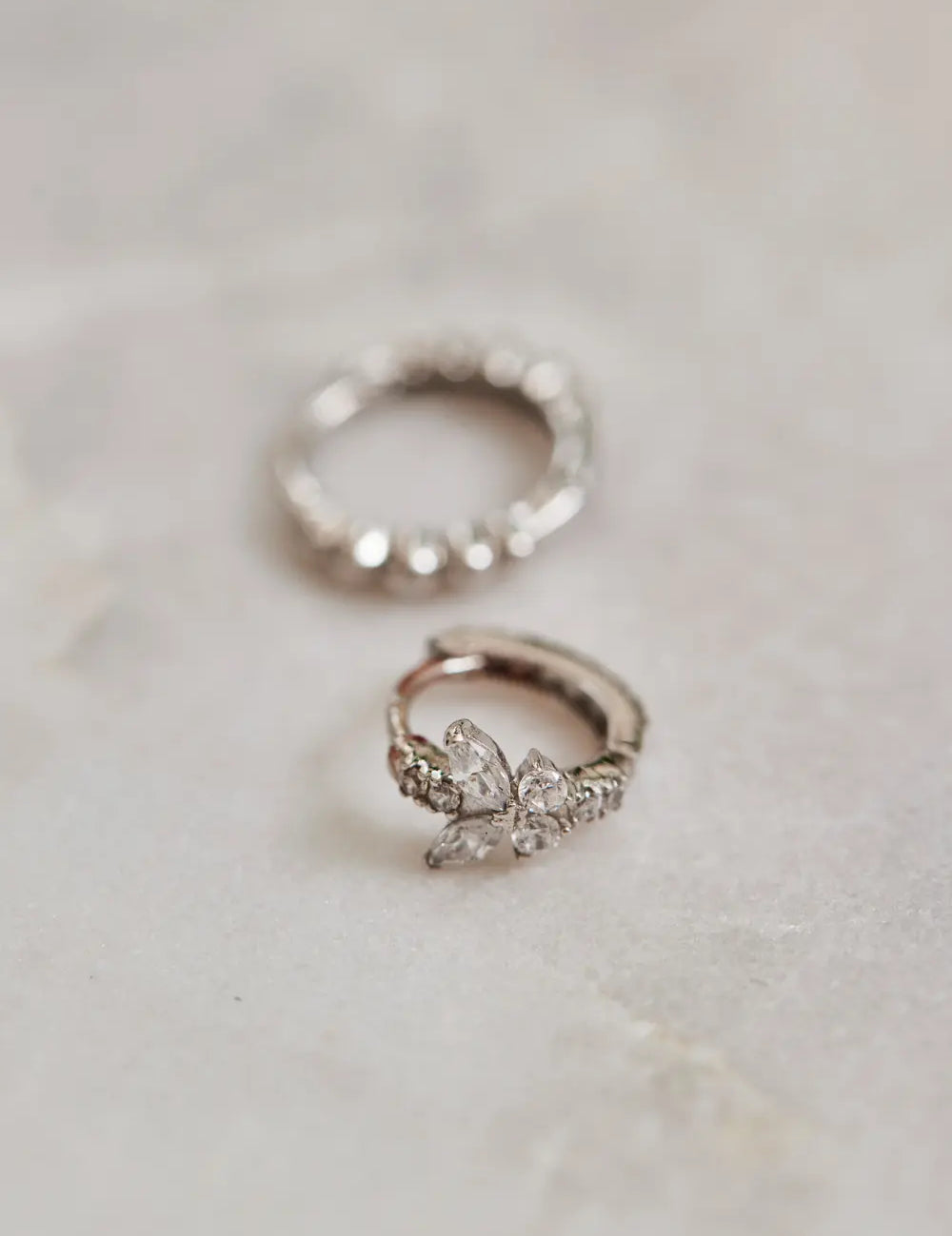 White gold hoop earrings lie on marble