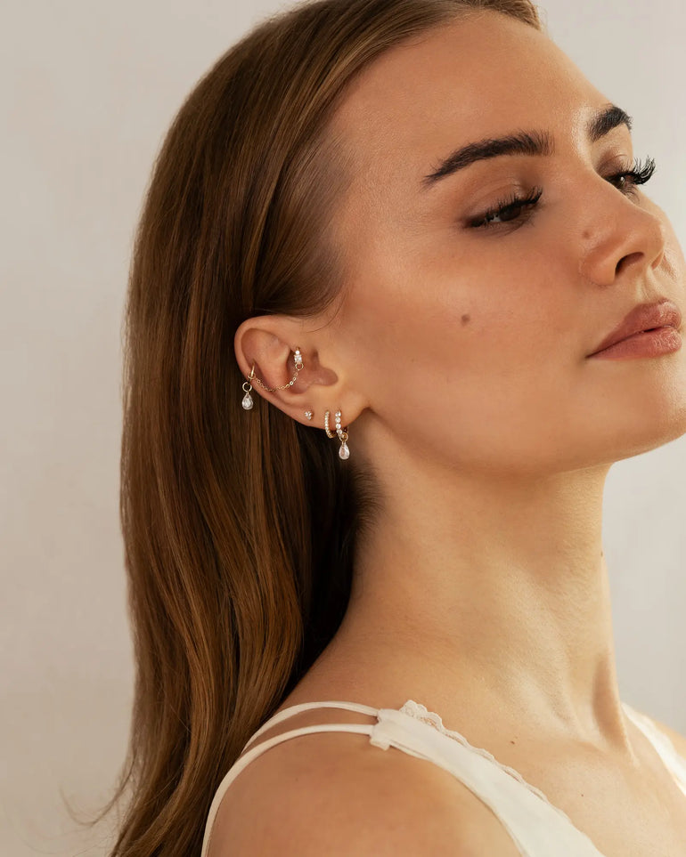 Gesichtsfoto eines Model mit einem Ohr, dass mit vielen Ohr Piercings geschmückt ist.