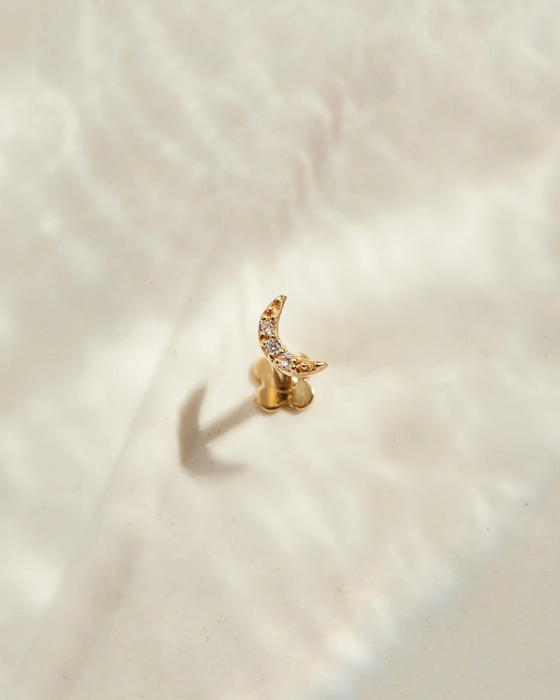 image_Moon ear stud stands on a beige surface