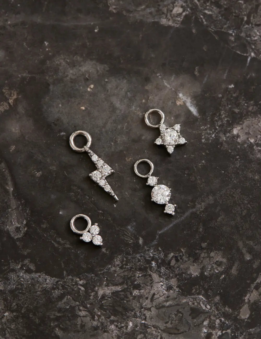 White gold earring pendants lie on marble