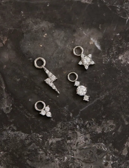 Weißgoldene Ohrring Anhänger liegen auf Marmor