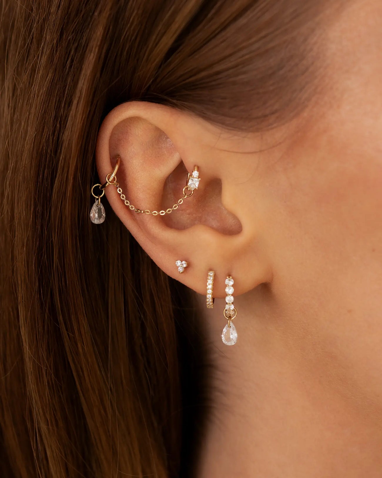 Ohr mit vielen Ohr Piercings und einen Ketten Anhänger an der Position eines Industrial Piercing