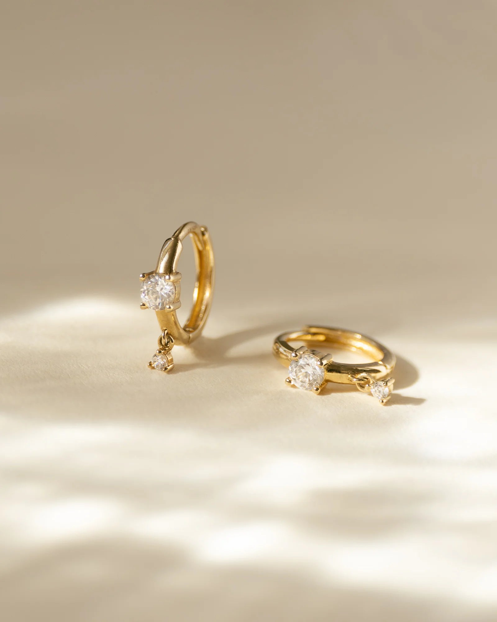 image_Lilli Creolen Gold liegen auf einer beigen Fläche