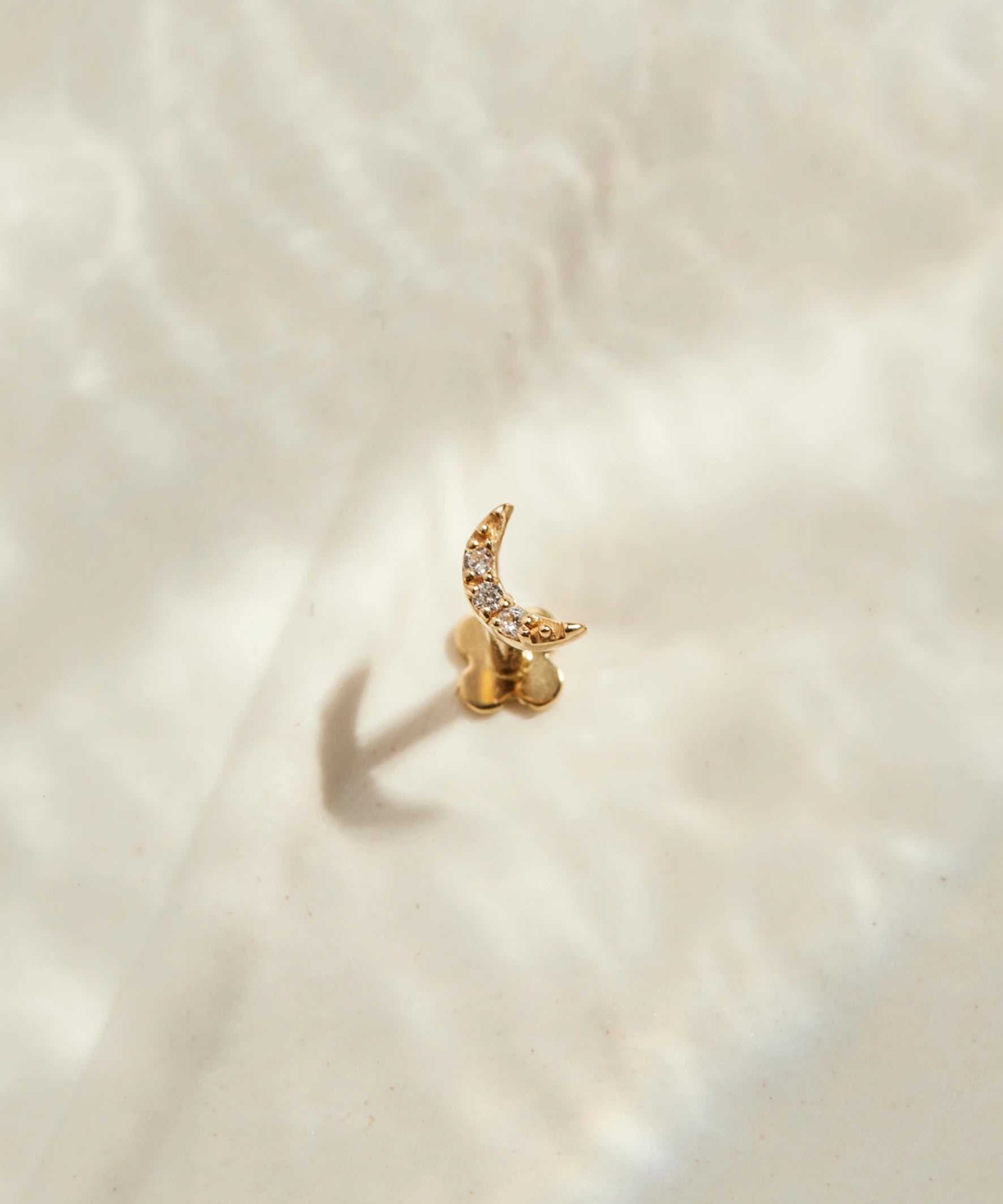 Mond Ohrstecker Gold steht auf einer beigen Oberfläche