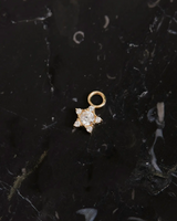 Produktfoto des Stern Ohrring Charms Gold auf schwarzen Mamor liegend