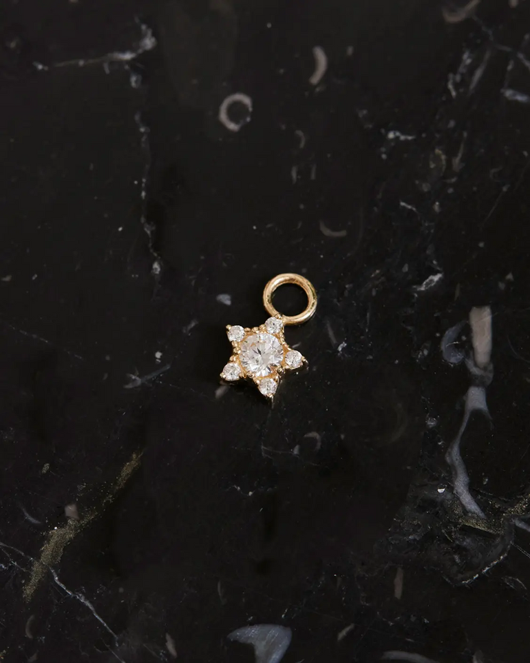 Produktfoto des Stern Ohrring Charms Gold auf schwarzen Mamor liegend